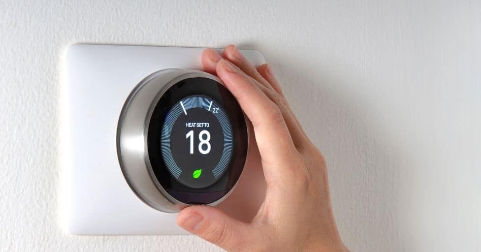 person adjusting a smart thermostat