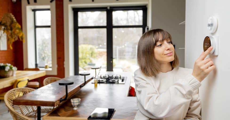 lady adjusting a smart thermostat in her home